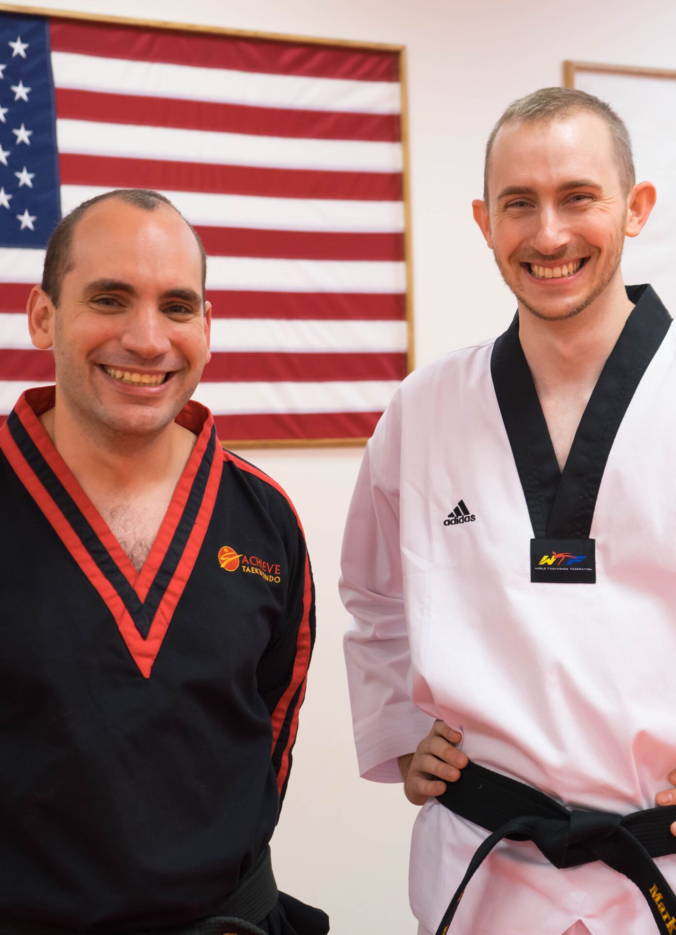 Two men in taekwondo uniforms smiling for a picture